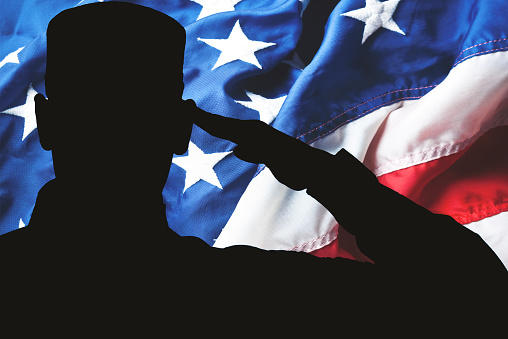 Silhouette of person saluting American flag
