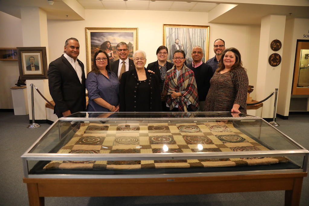 Chancellor Robin Cummings, Harvey Godwin Jr., Emma Locklear, pose with the quilt along with museum staff and staff members with the Southeast American Indian Studies program
