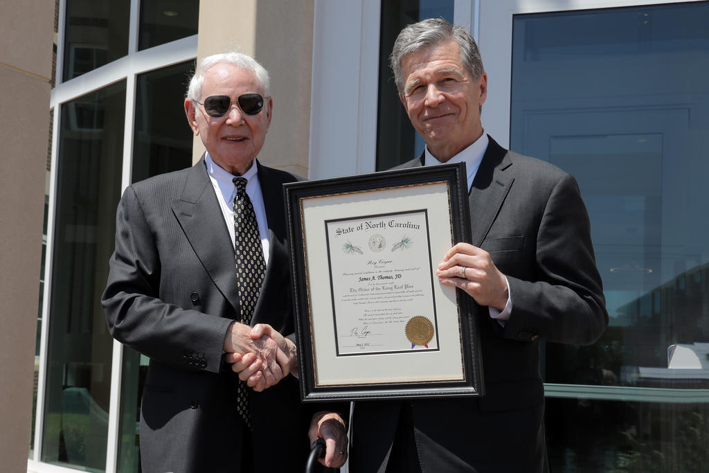 Gov. Roy Cooper (right) presents Jim Thomas with the Order of the Long Leaf Pine