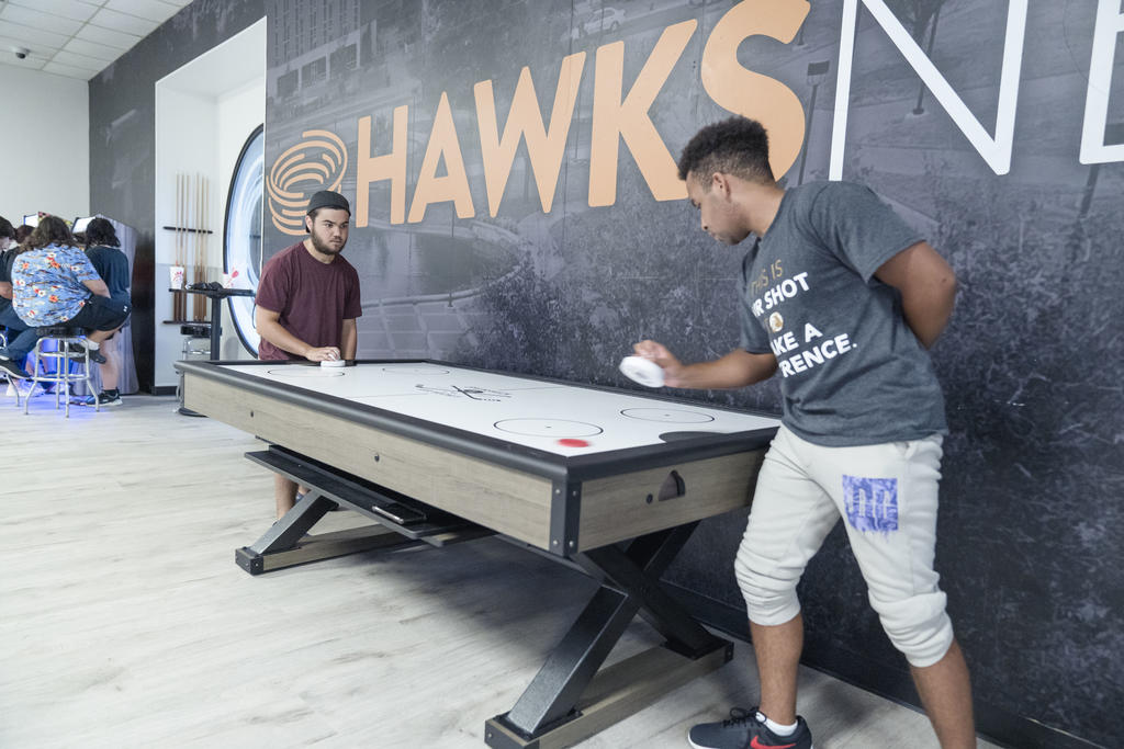 Two men playing air hockey in the Hawks Nest