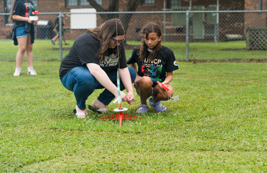 UNCP student counselor Zoe Polley assists a camper during the rocket launch at the Cummings Aerospace Engineering Camp