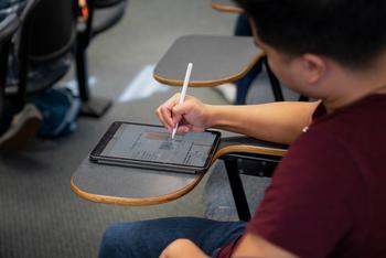 A student using a tablet on a desk.