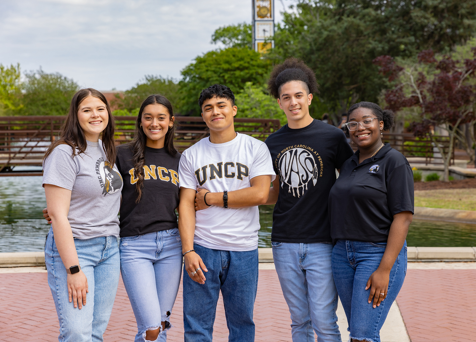students on UNC Pembroke quad in front of bridge and water feature