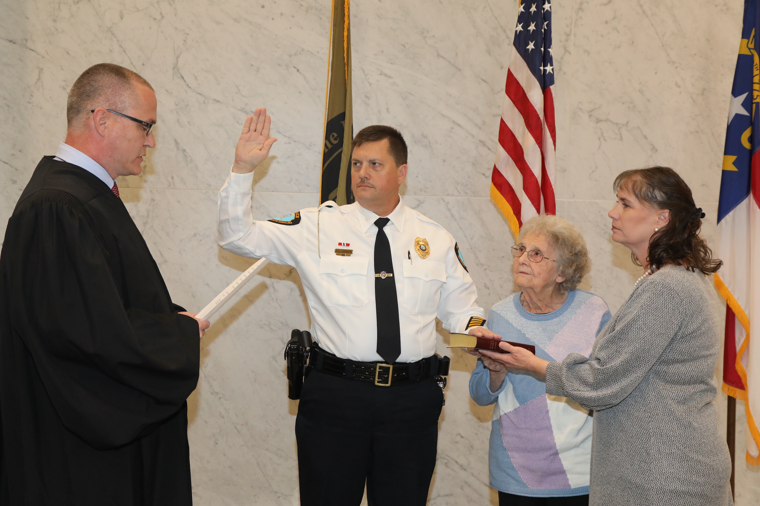 NC Supreme Court Justice and UNCP alumnus Trey Allen administers the oath of office to Chief George Earl Johnson as Johnson's mother, Ruby, and wife, Sonya, look on