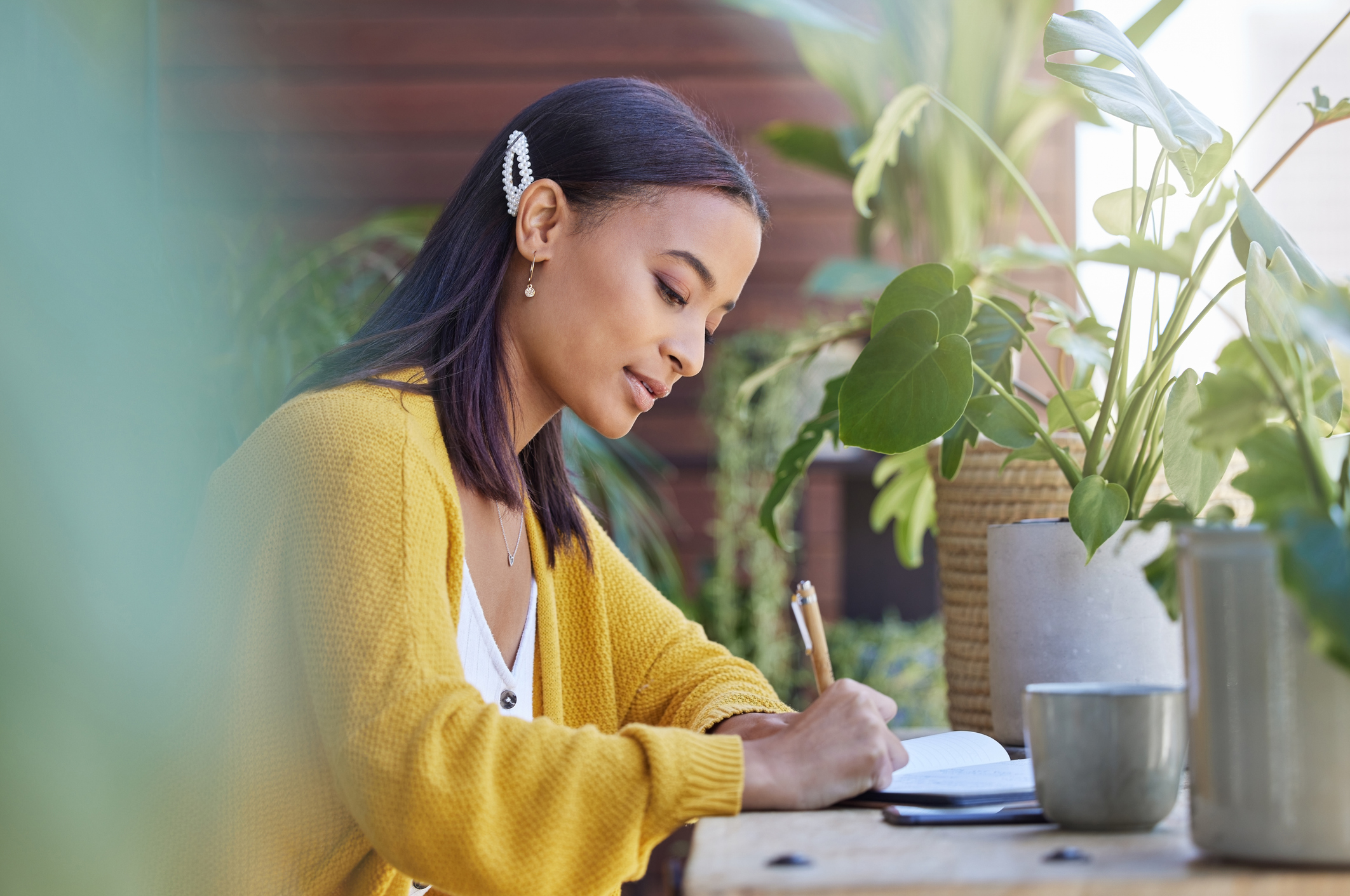 Young female writing near plant