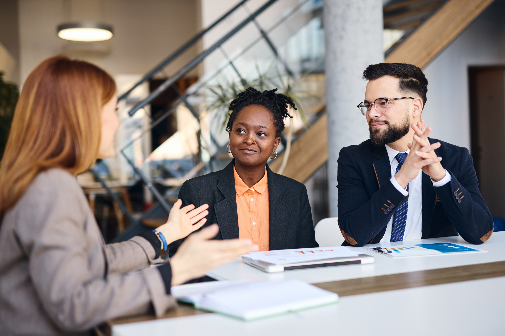 Business woman and males sitting at a table talking to each other