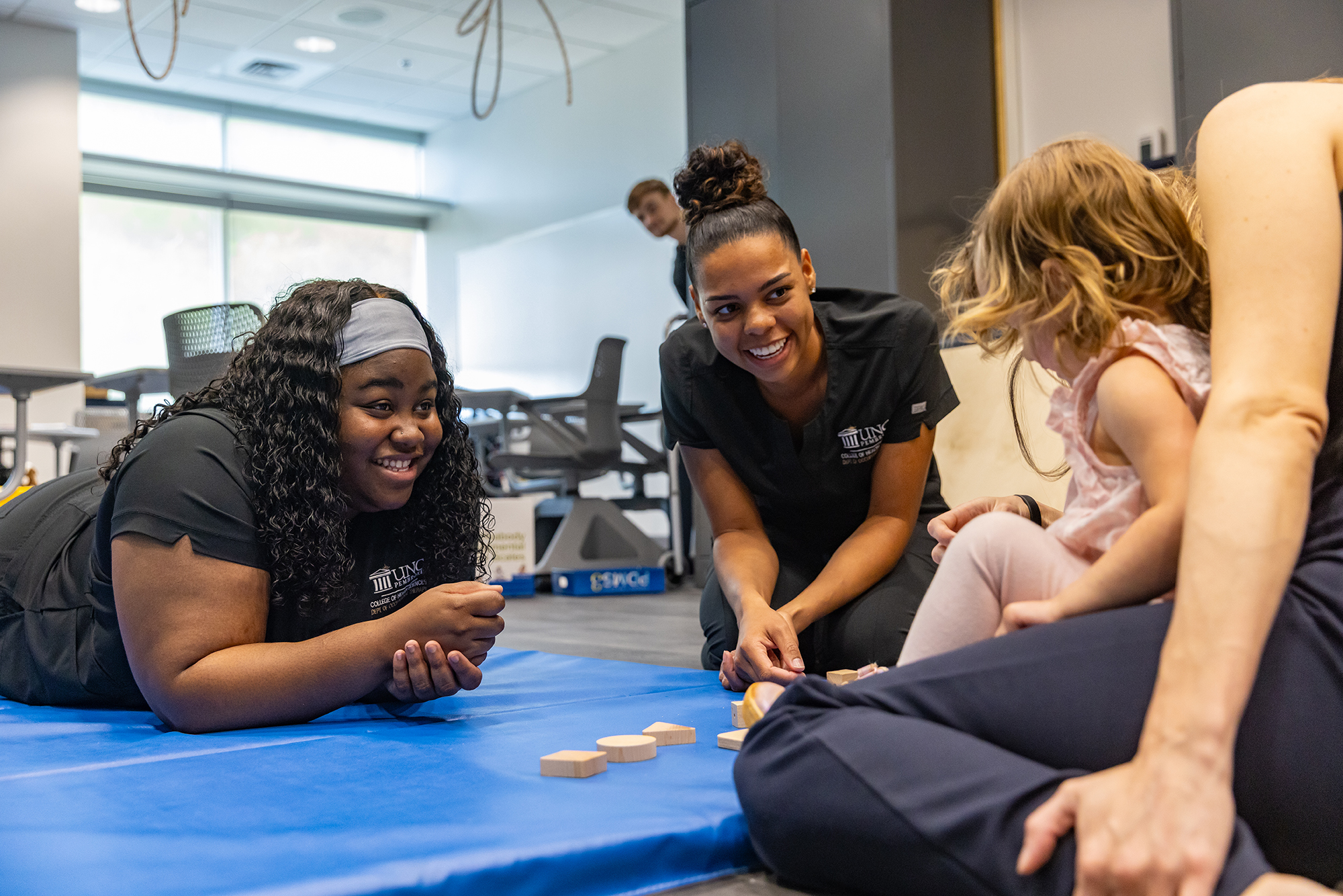 female OT students on the floor with a child at UNCP 