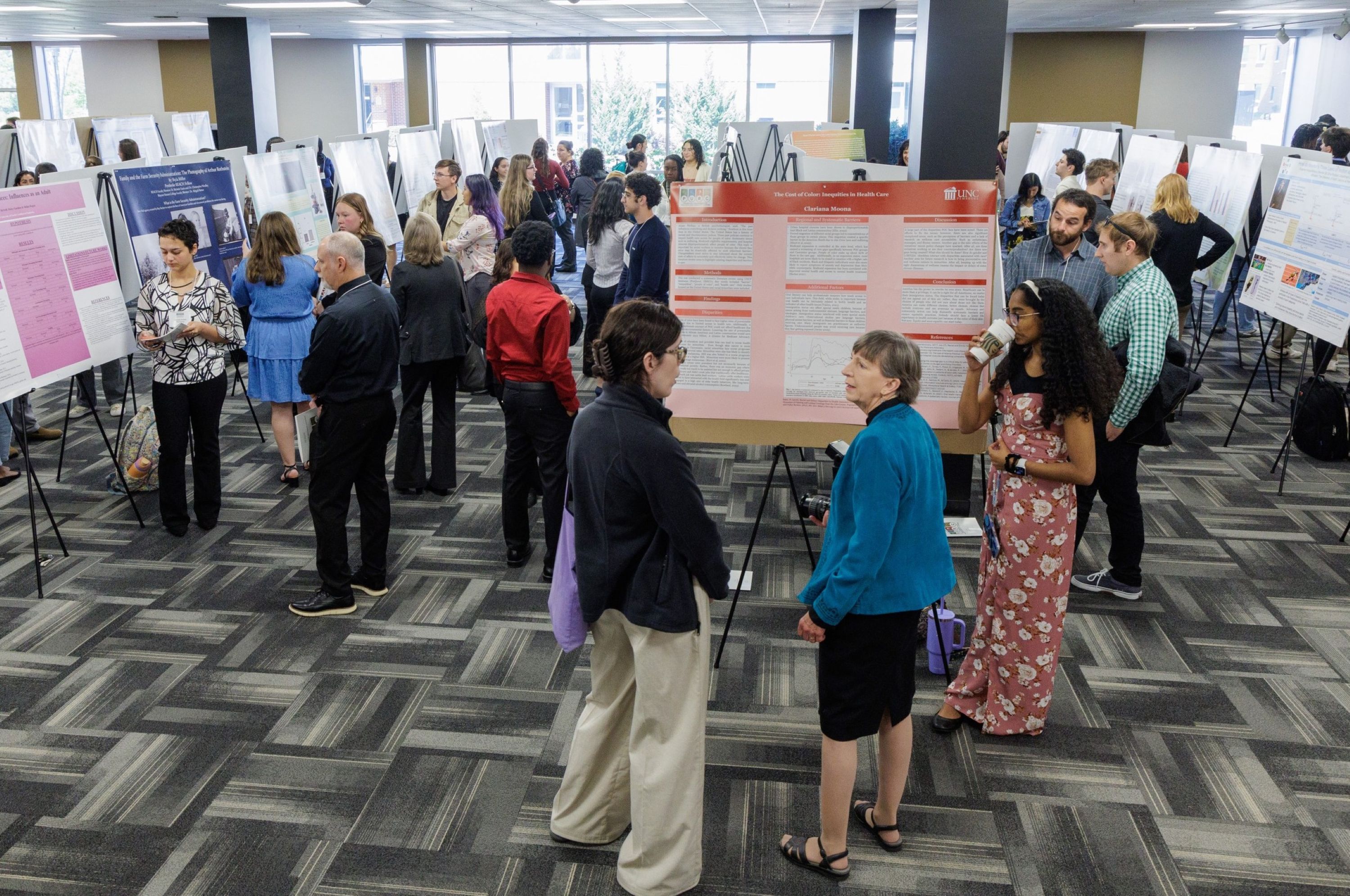 Symposium participants and attendees talking during a poster session in the Livermore Library.