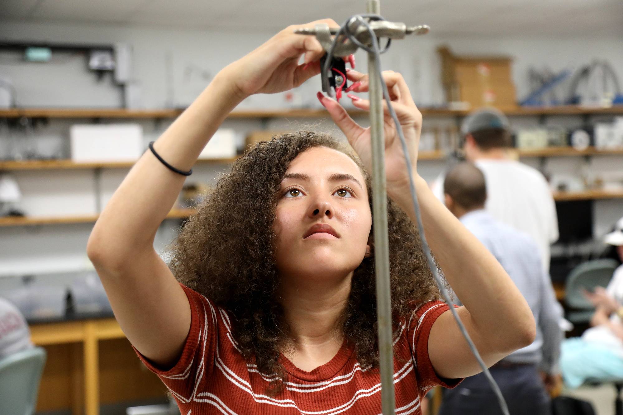 female student inspecting science equipment in a physics lab at UNC Pembroke