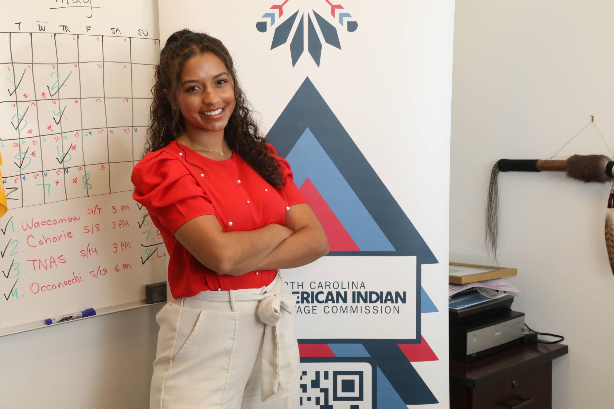 intern posing at her internship in front of a banner.