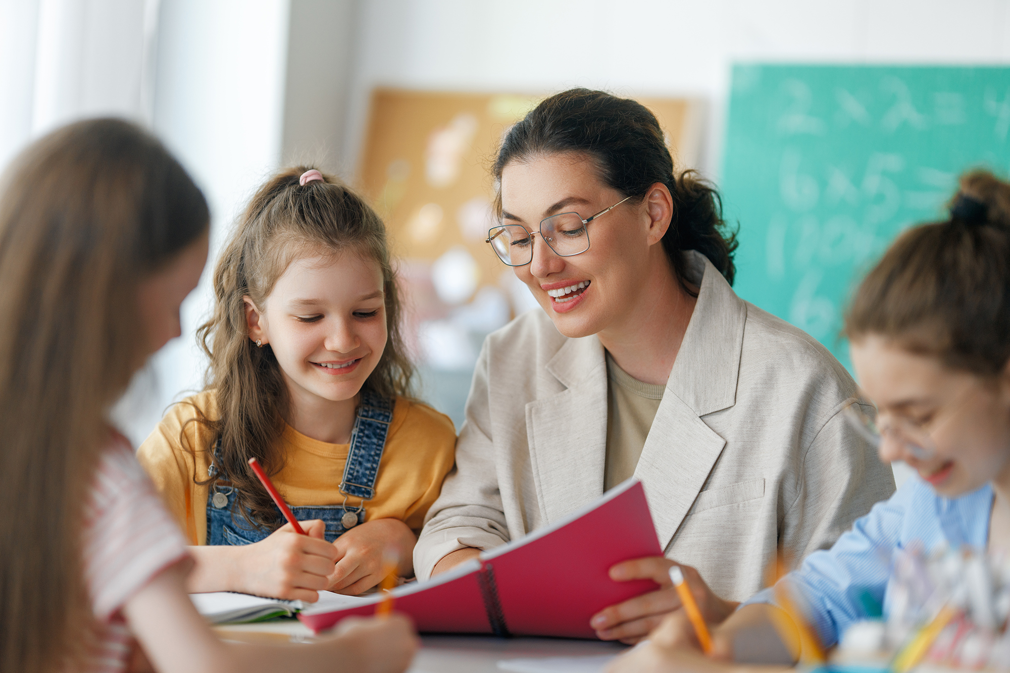 A teacher works closely with students in a classroom, representing the Academically or Intellectually Gifted Education program at UNCP.
