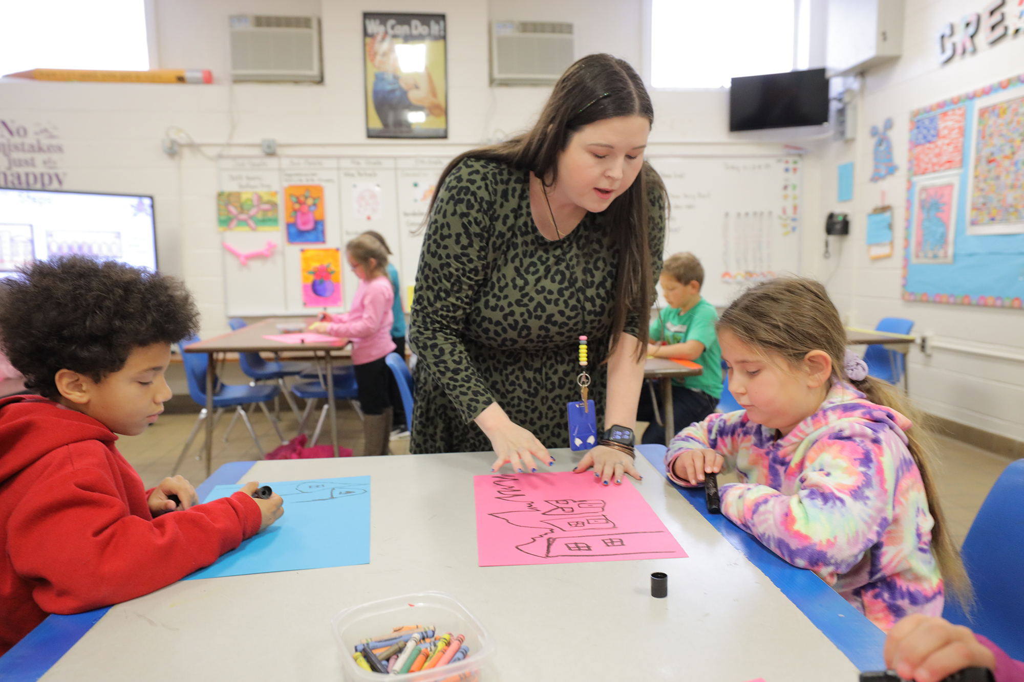 UNCP student teacher with two young elementary students doing art
