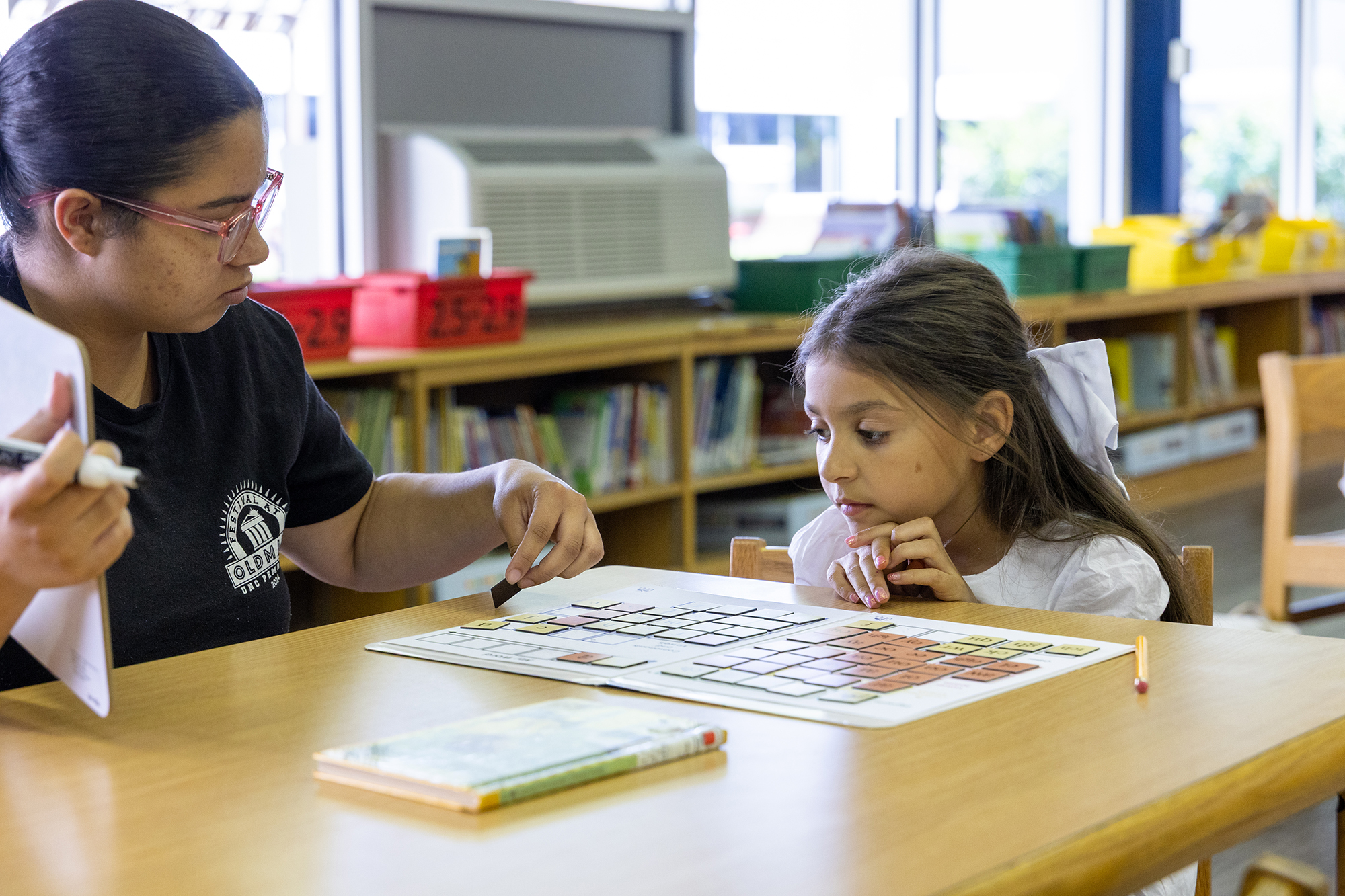 A UNCP School of Education student works with an elentary-aged girl on a reading assignment at Pembroke Elementary School.
