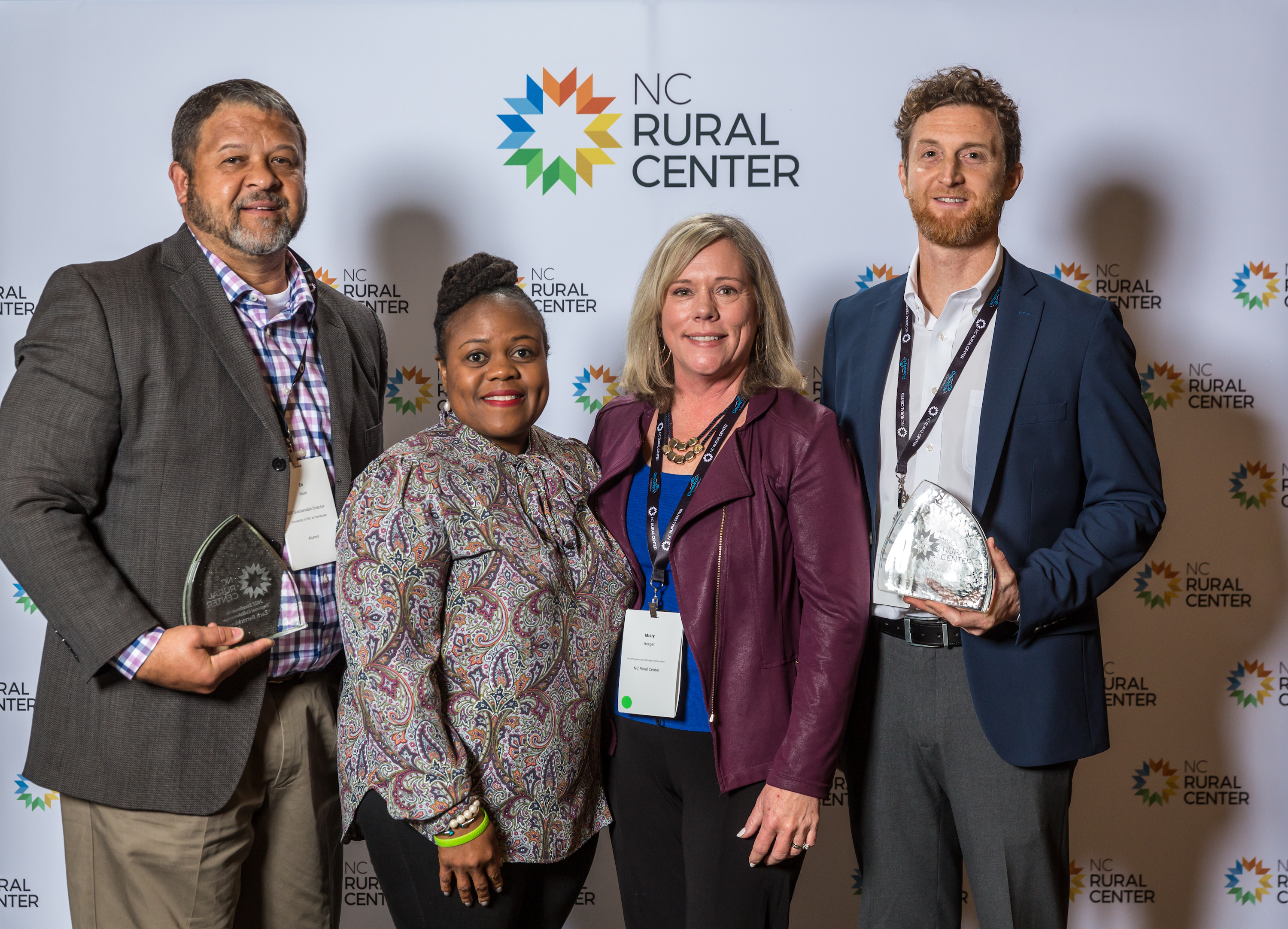 Ed Hunt and others standing and posing in front of a backdrop after receiving an award