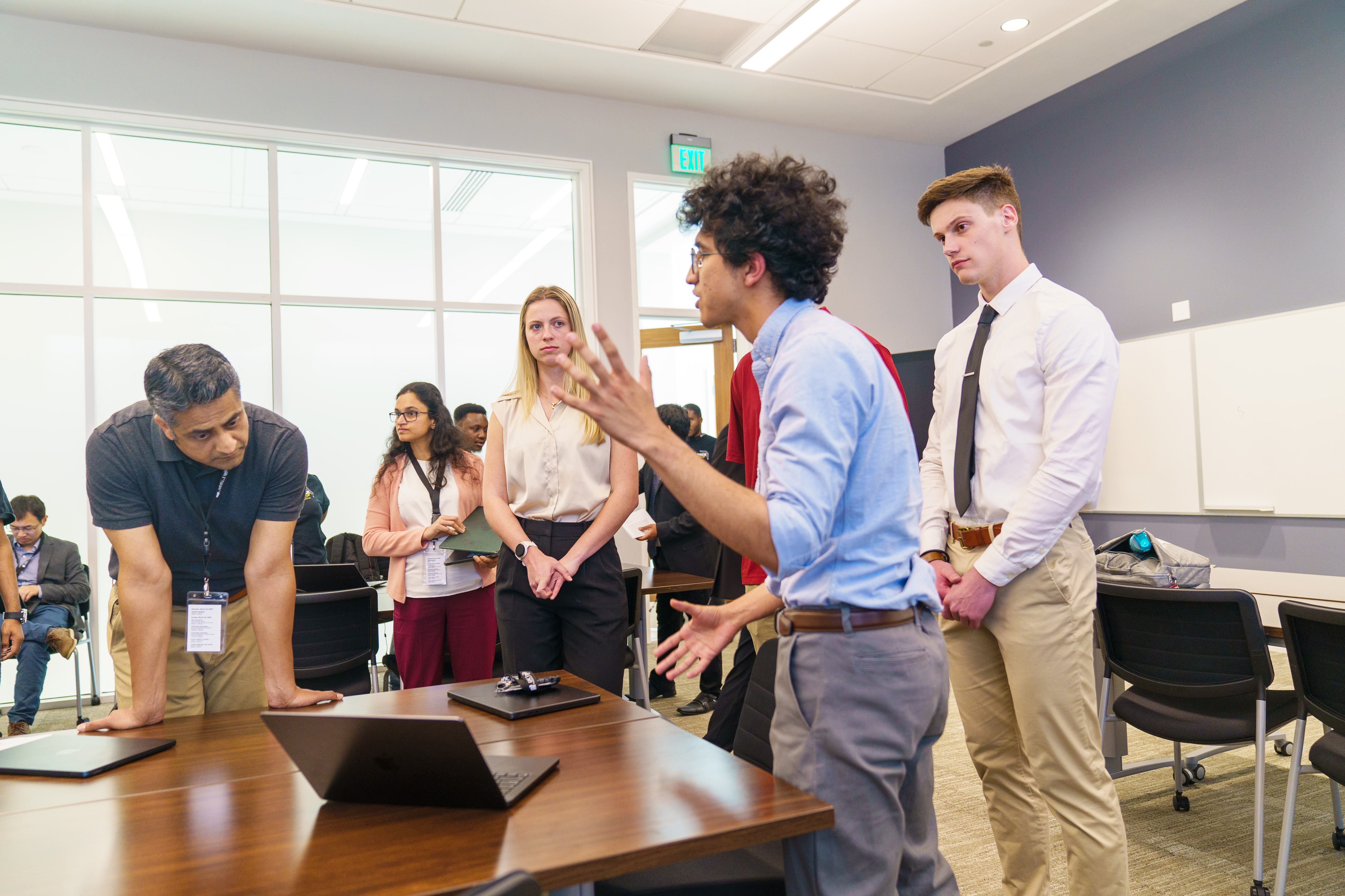 students stand around a laptop in a business classroom at UNC Pembroke