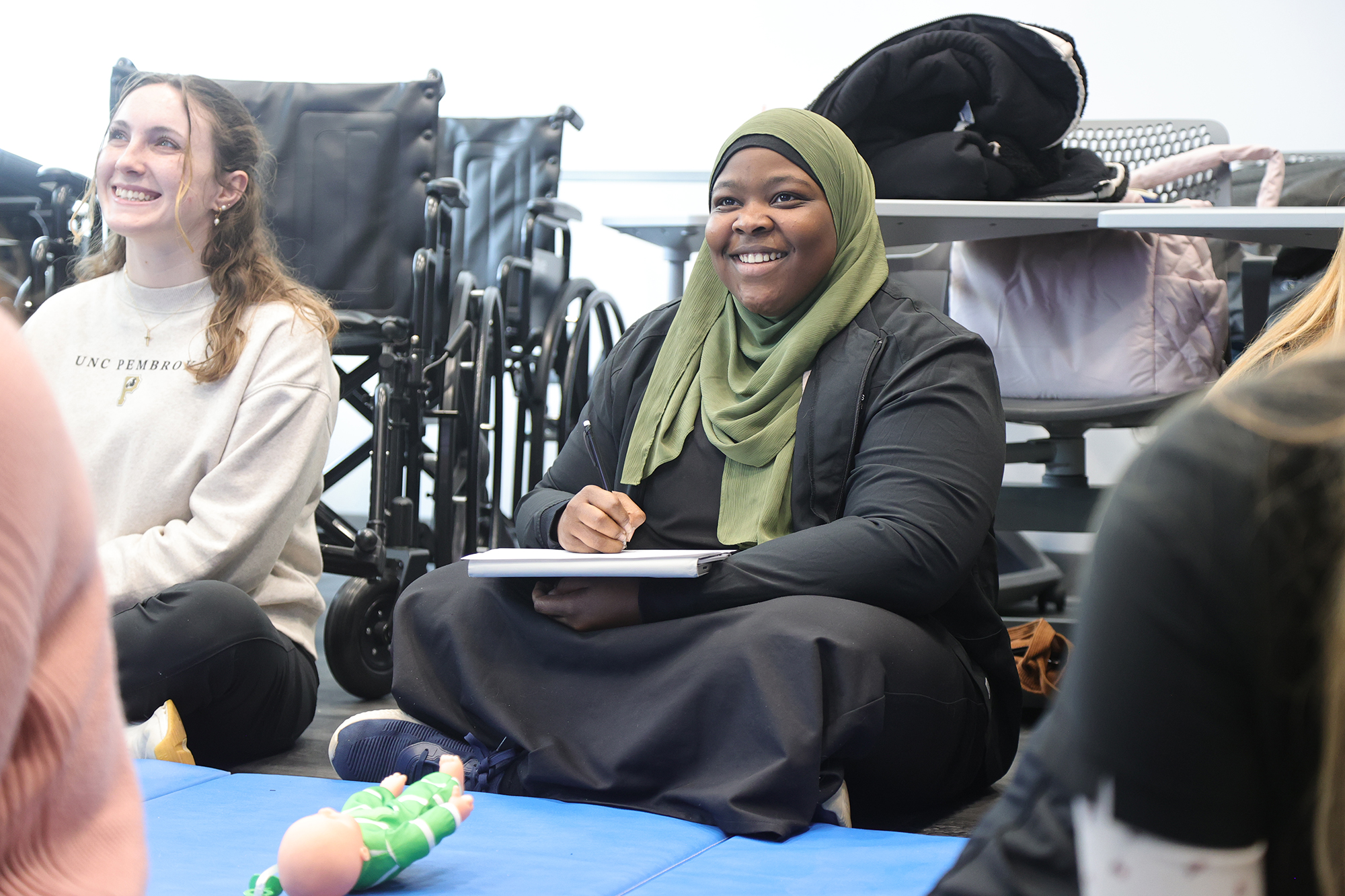 UNCP students sit on a floor in the MSOT lab taking notes.