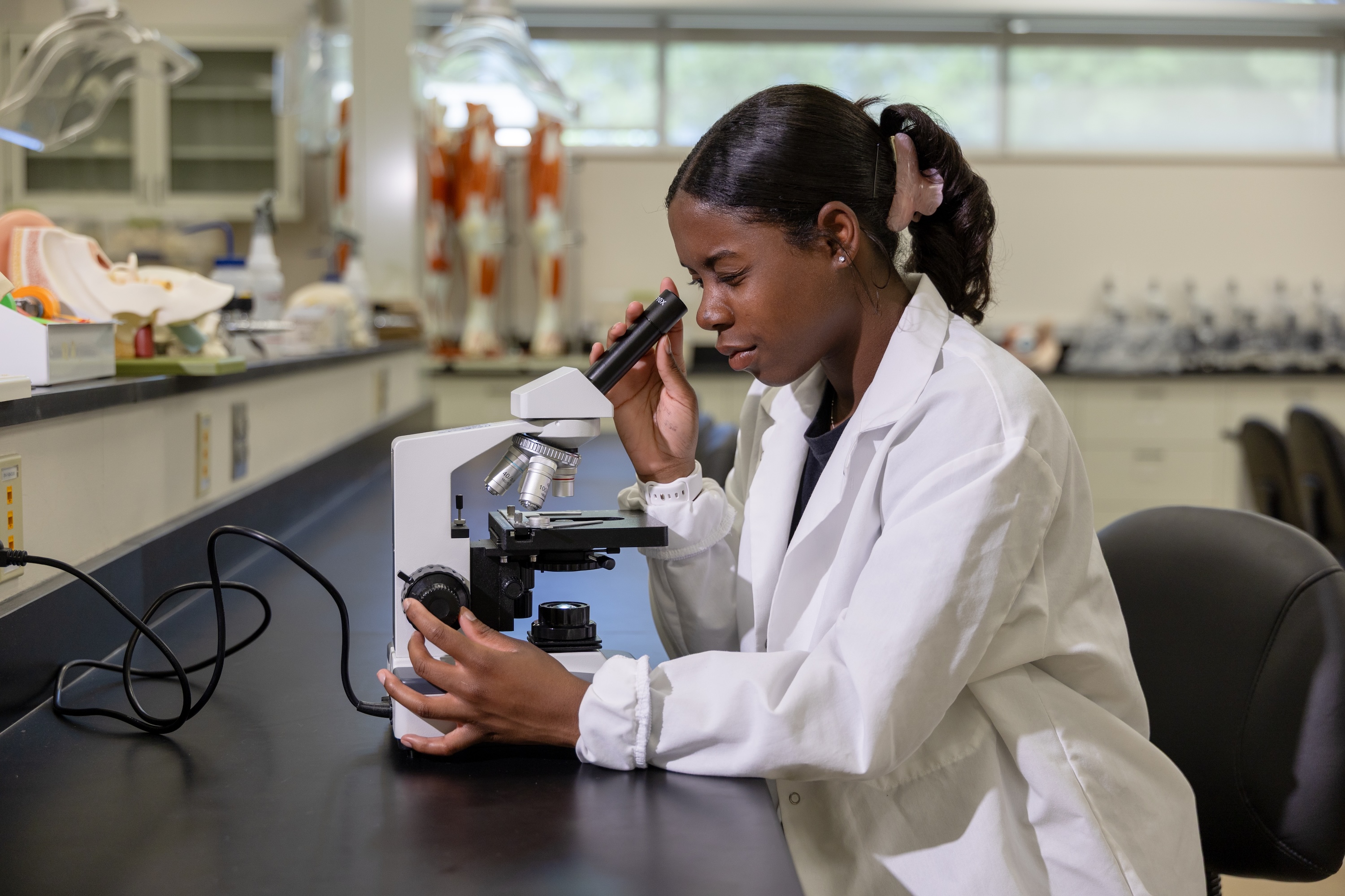 Eugenie Amidou looks through microscope lens
