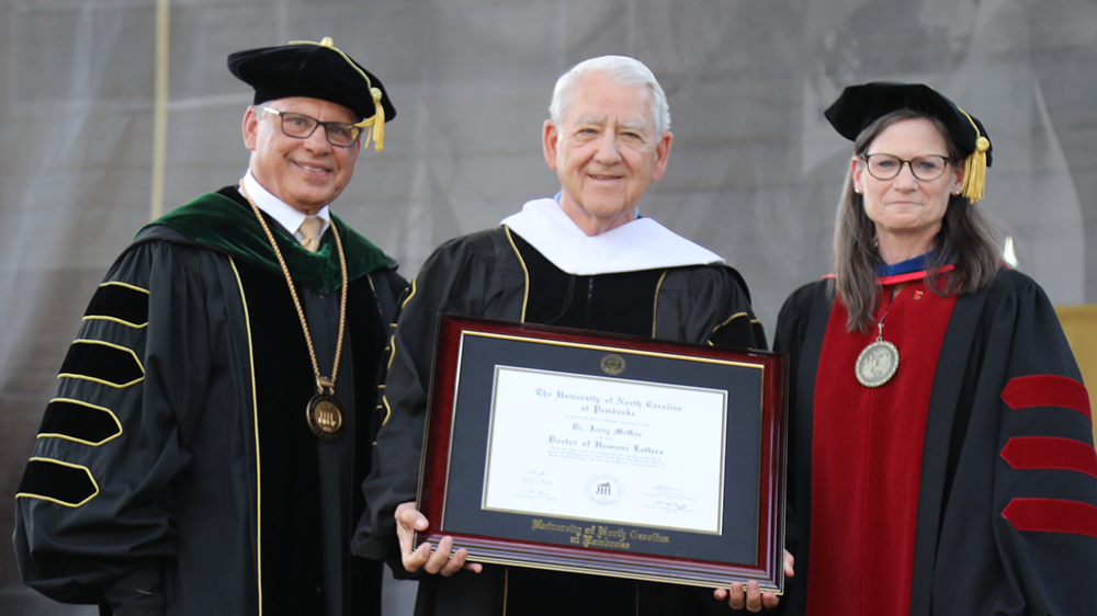 UNCP Chancellor Robin Cummings, honoree Jerry McGee, Provost Diane Prusank on stage at the UNCP commencement.