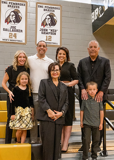 The Sampson family poses in front of Ned Sampson's retired No. 12 jersey at the English E. Jones Center.