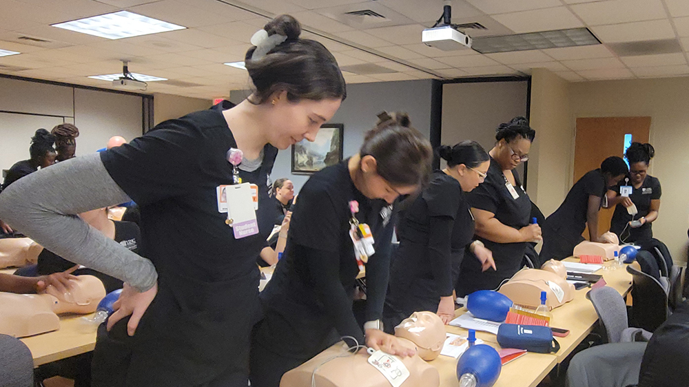 nursing students with a training mannequin