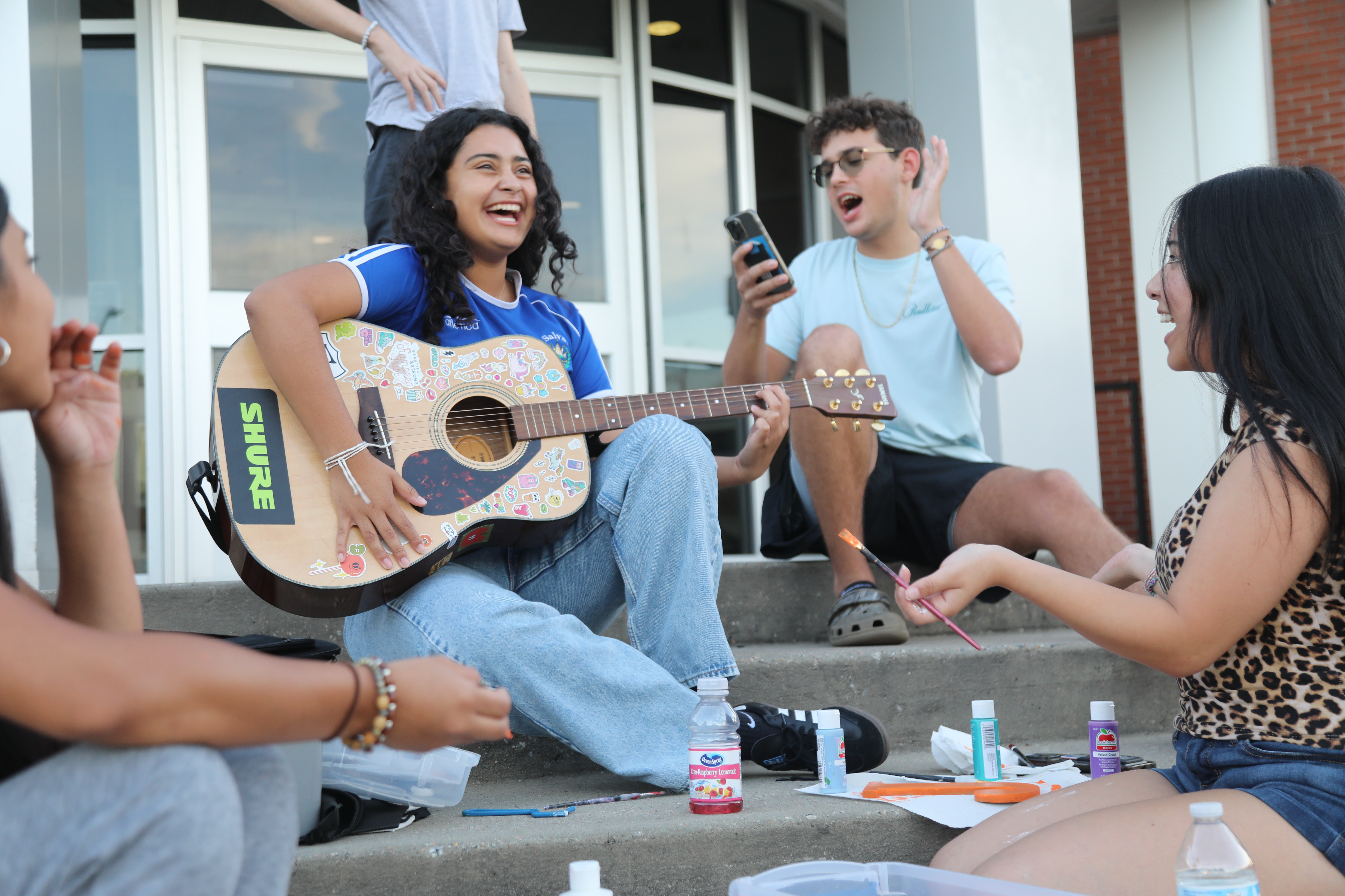 Students playing guitar on the steps outside of Oak Hall