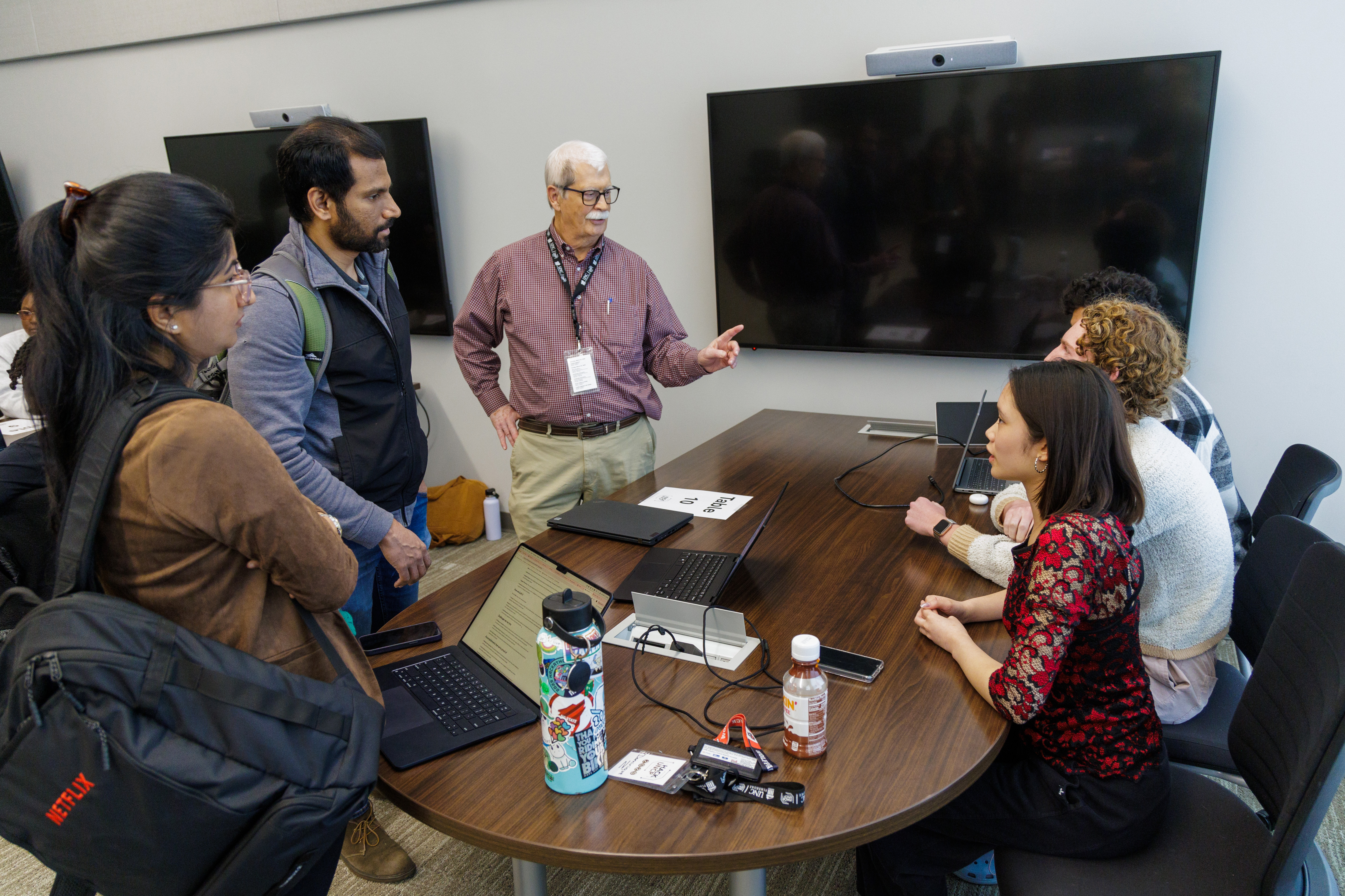 students and faculty stand around a computer and talk