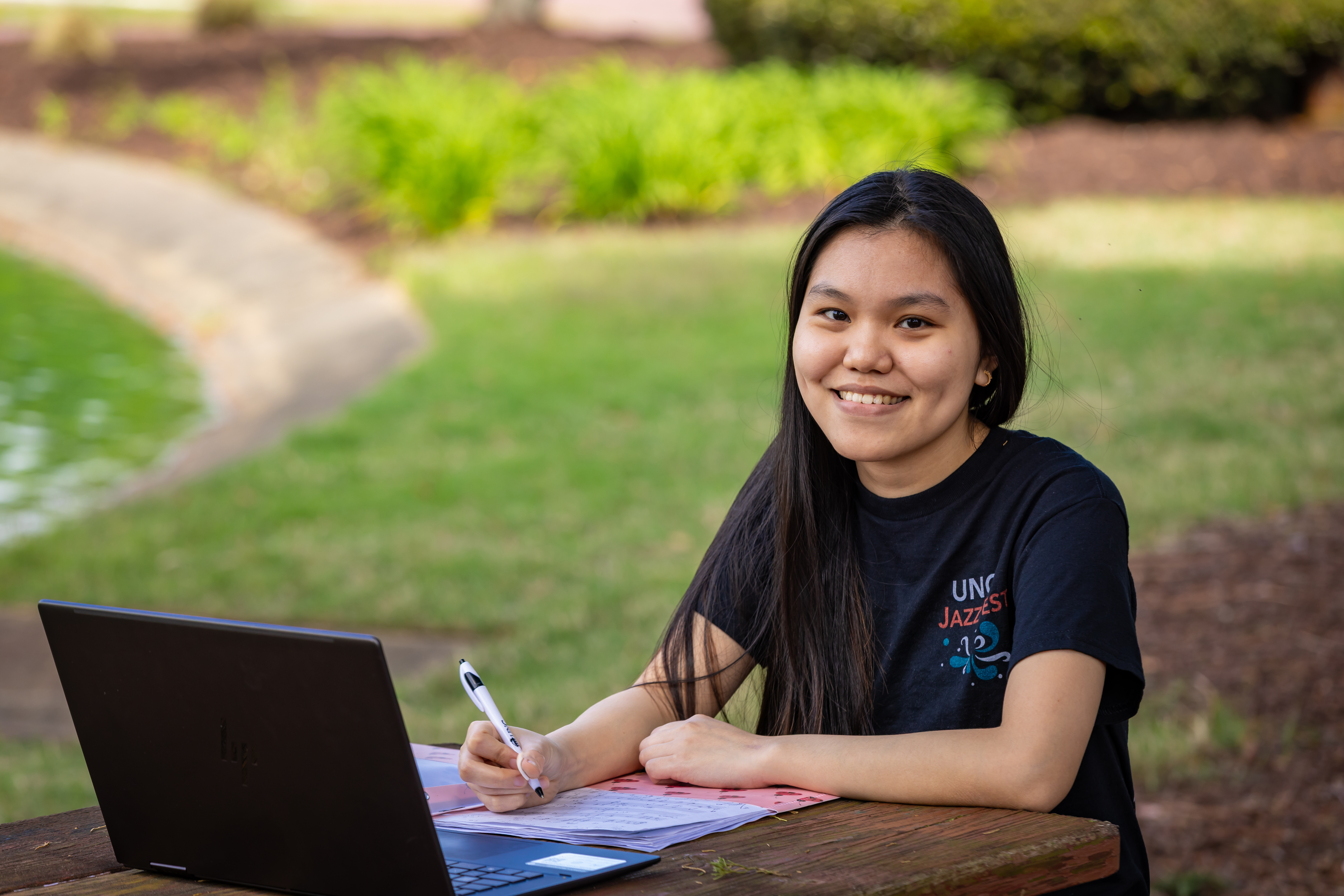 international student outside at picnic table with computer