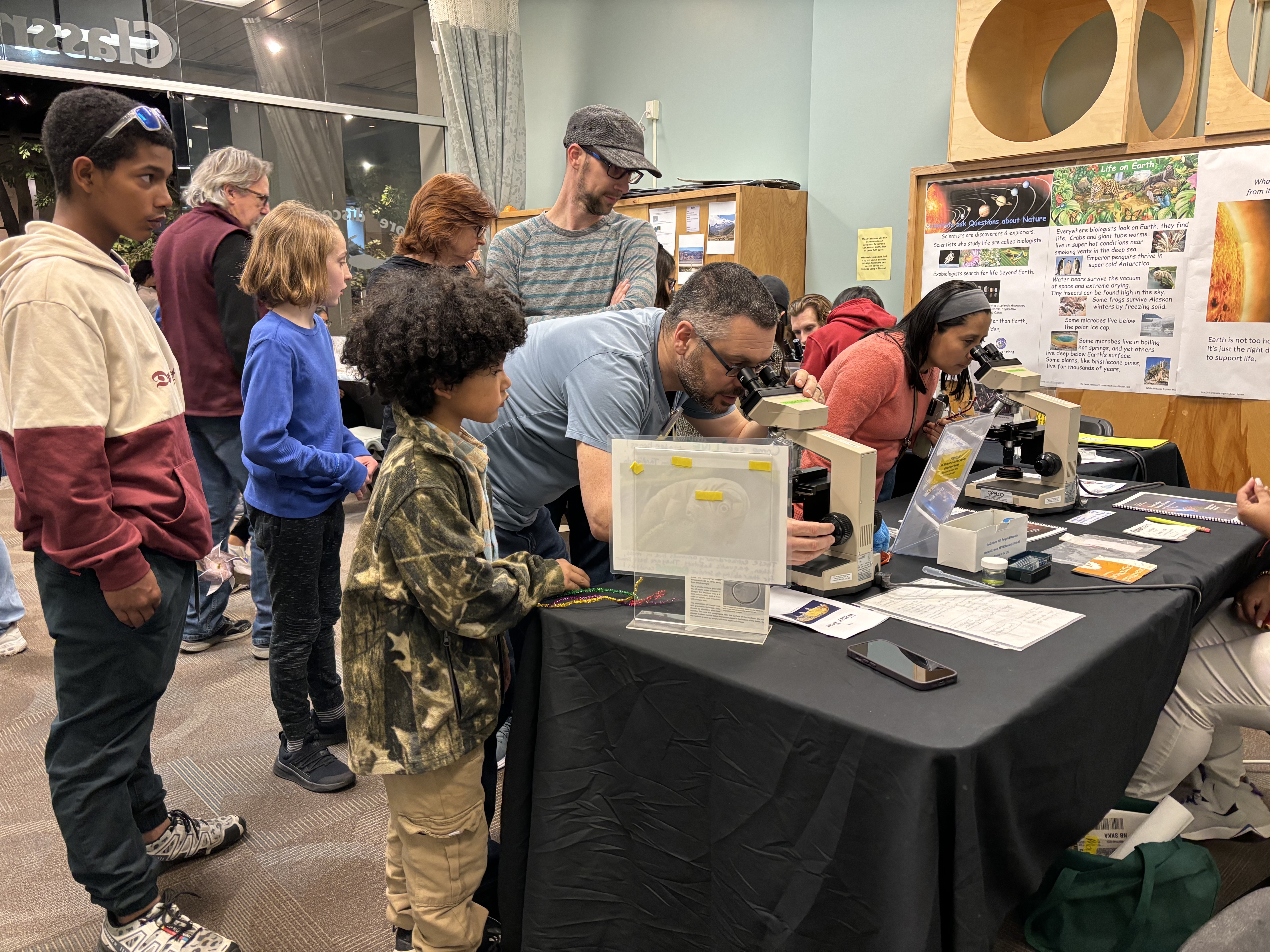 Students gather around a table to view telescopes