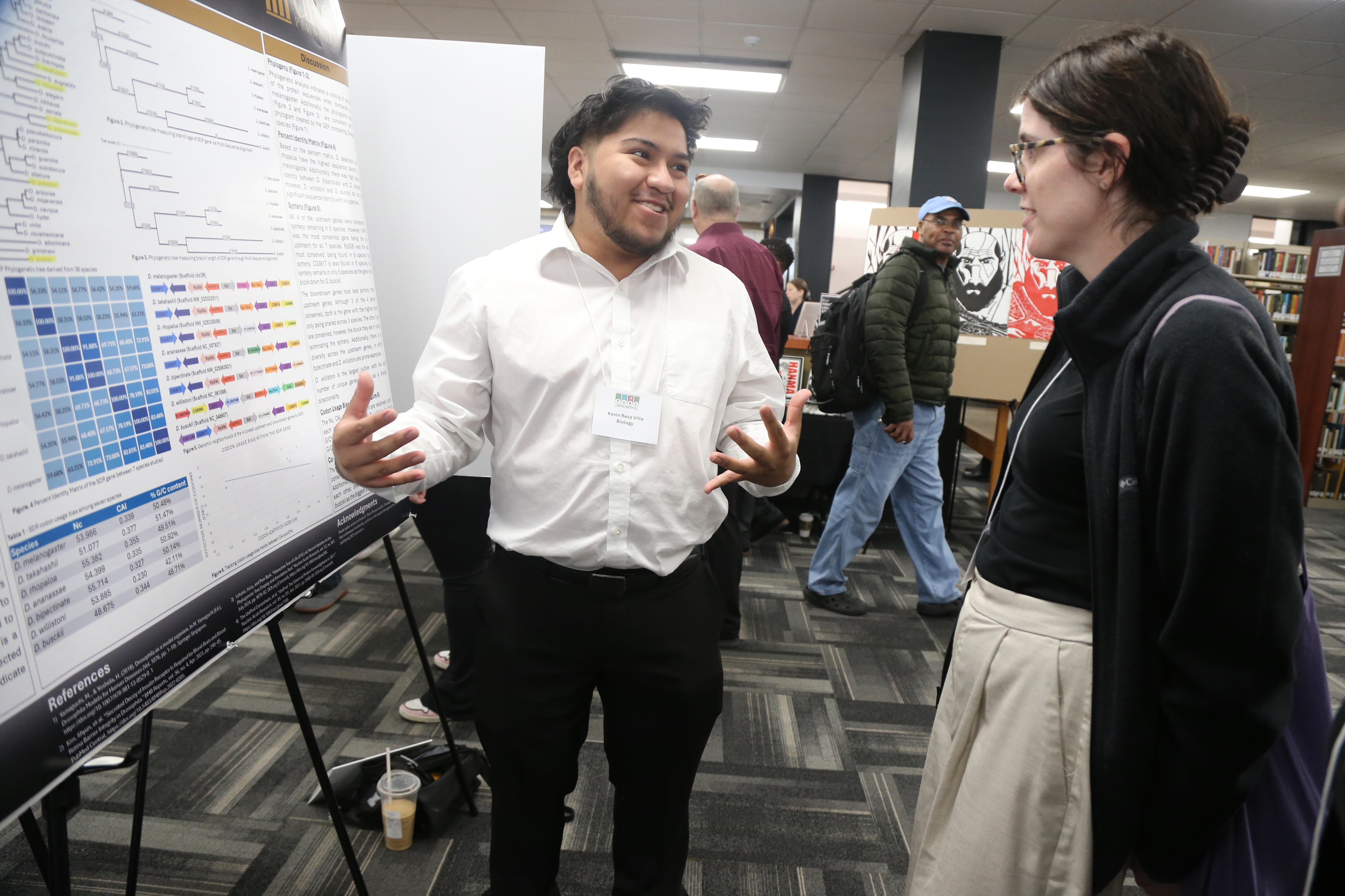 Kevin Reza-Villa speaks with a student about his research poster.