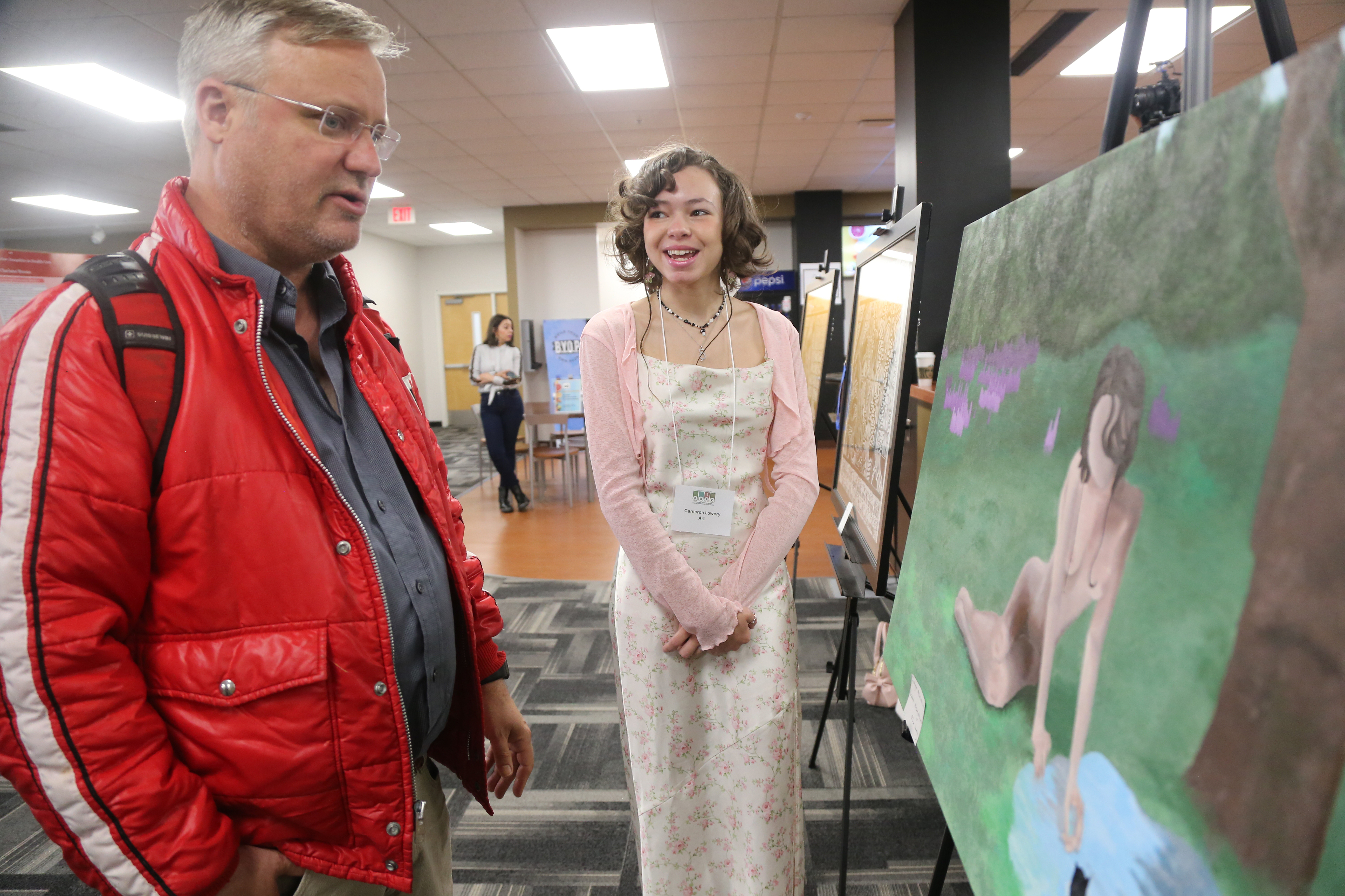 Art student Cameron Lowery discusses her artwork with Dr. Aaron Vandermeer.