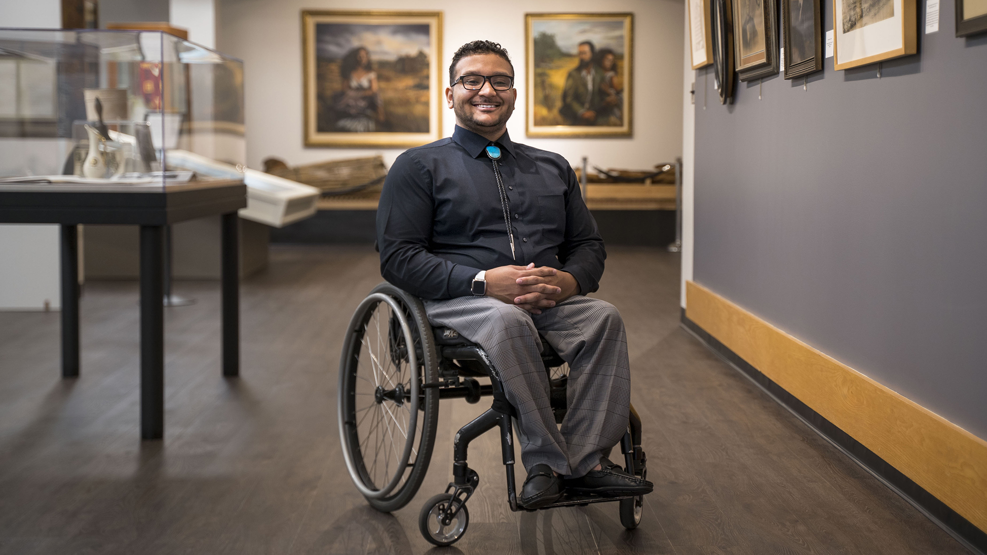 Benjamin Clark smiling inside Old Main with framed artwork and display cases around him.