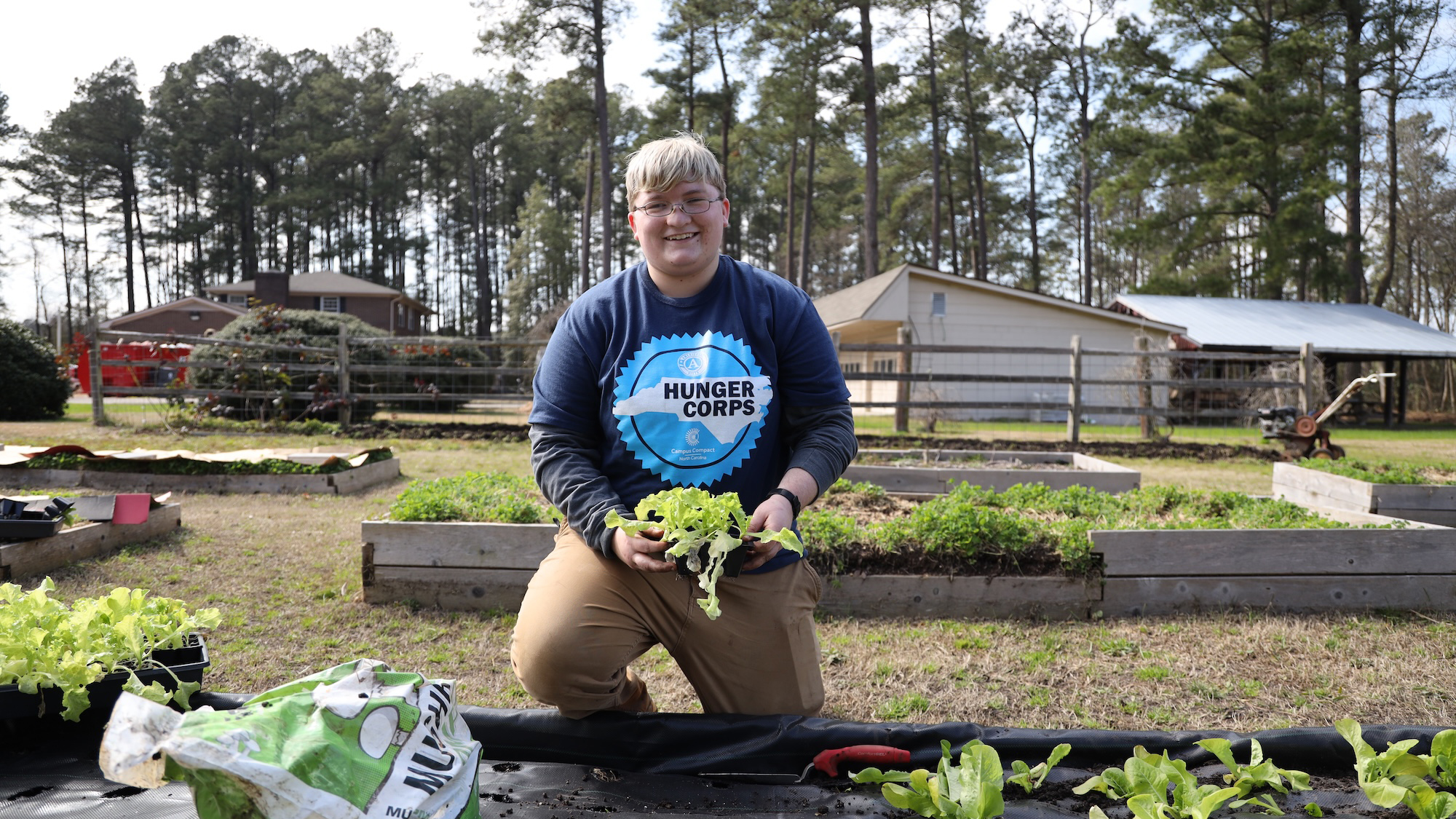 A student plants lettuce during a hands-on gardening session.