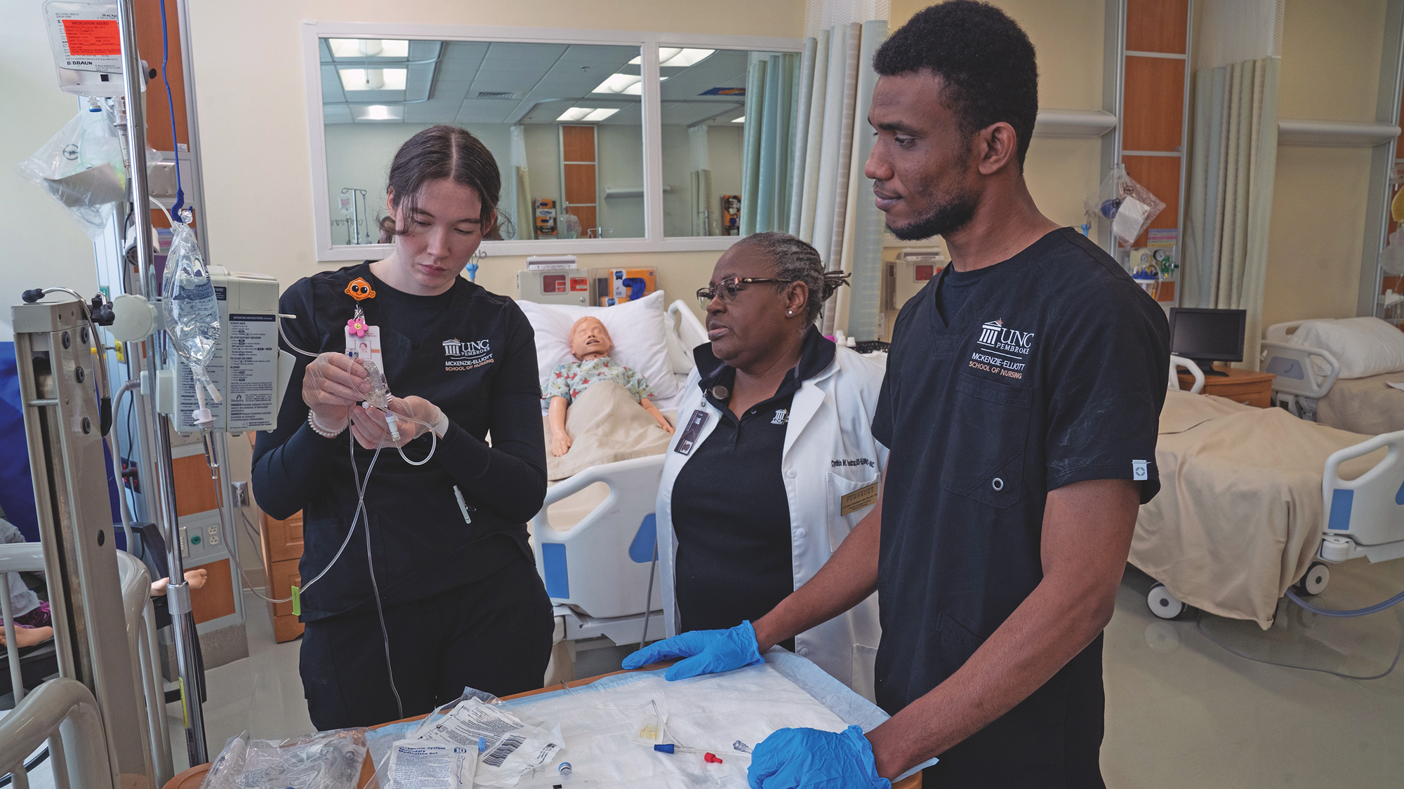 two student nurses get guidance from a professor during IV training