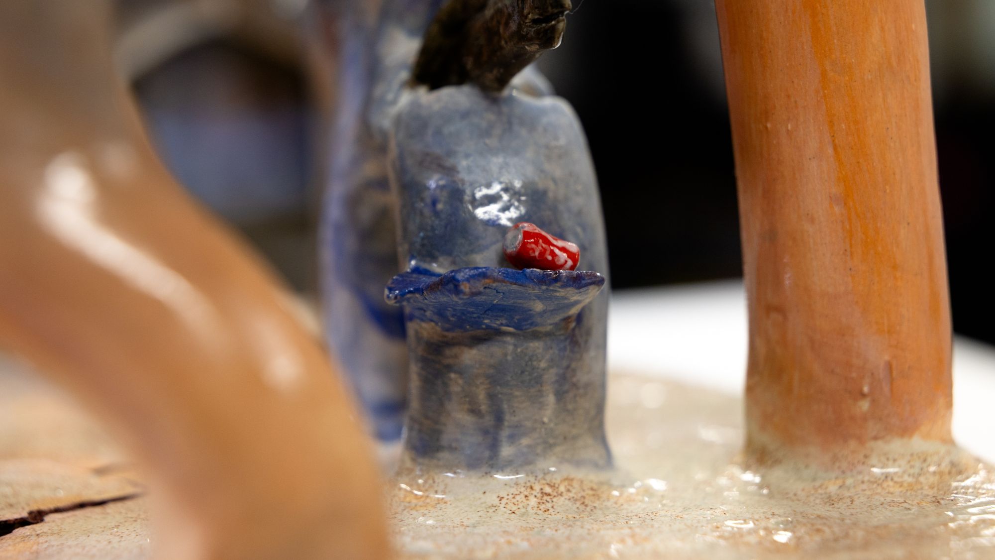 Close-up of Mia Baca’s coral sculpture showing a small red soda can tucked among blue and tan coral forms, highlighting pollution within the underwater scene.
