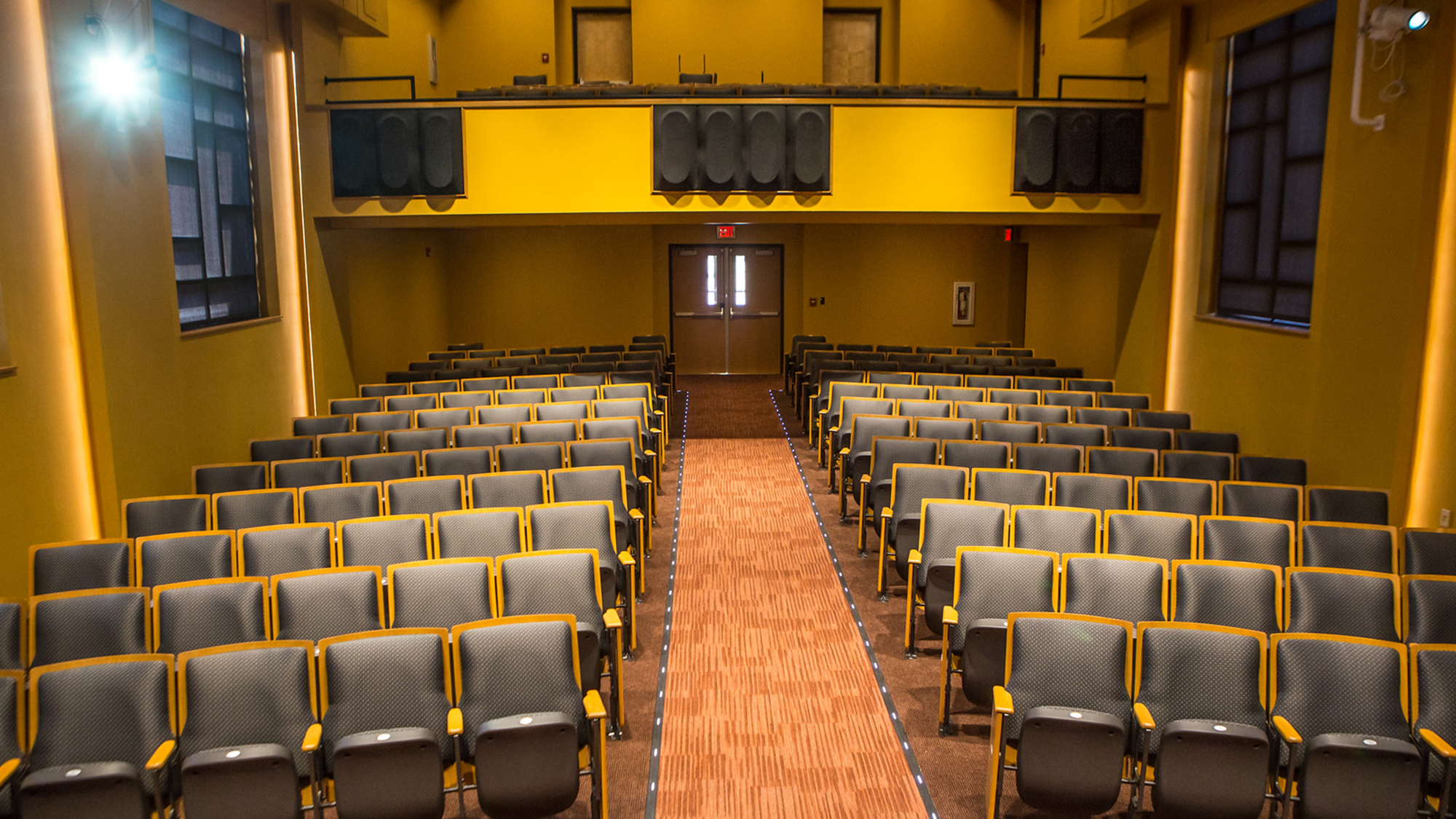 interior view of the Moore Hall Auditorium at UNC Pembroke, featuring rows of theater-style seating, a central aisle, and a balcony area, used for lectures, performances, and music education events.