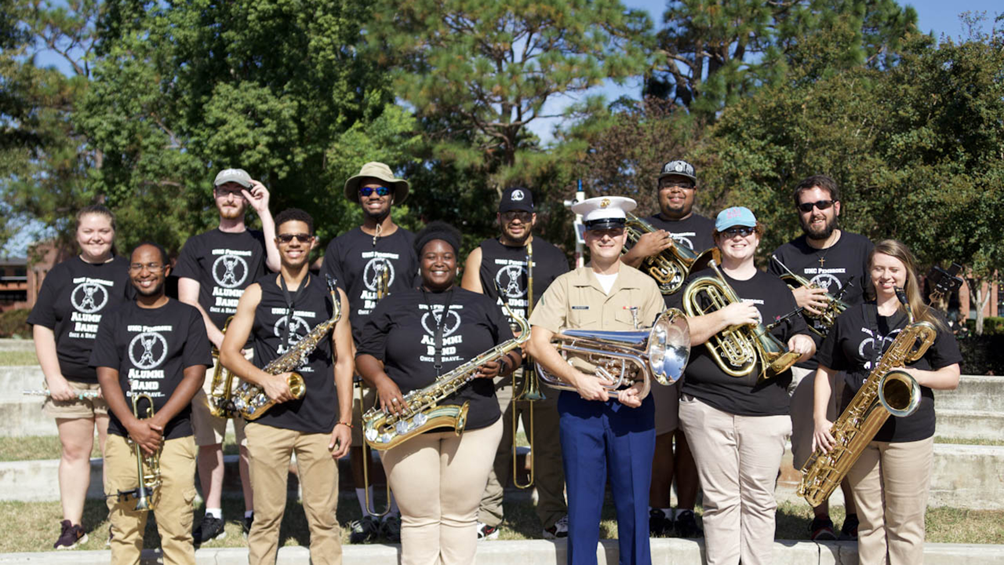 alumni pose on steps with their instruments