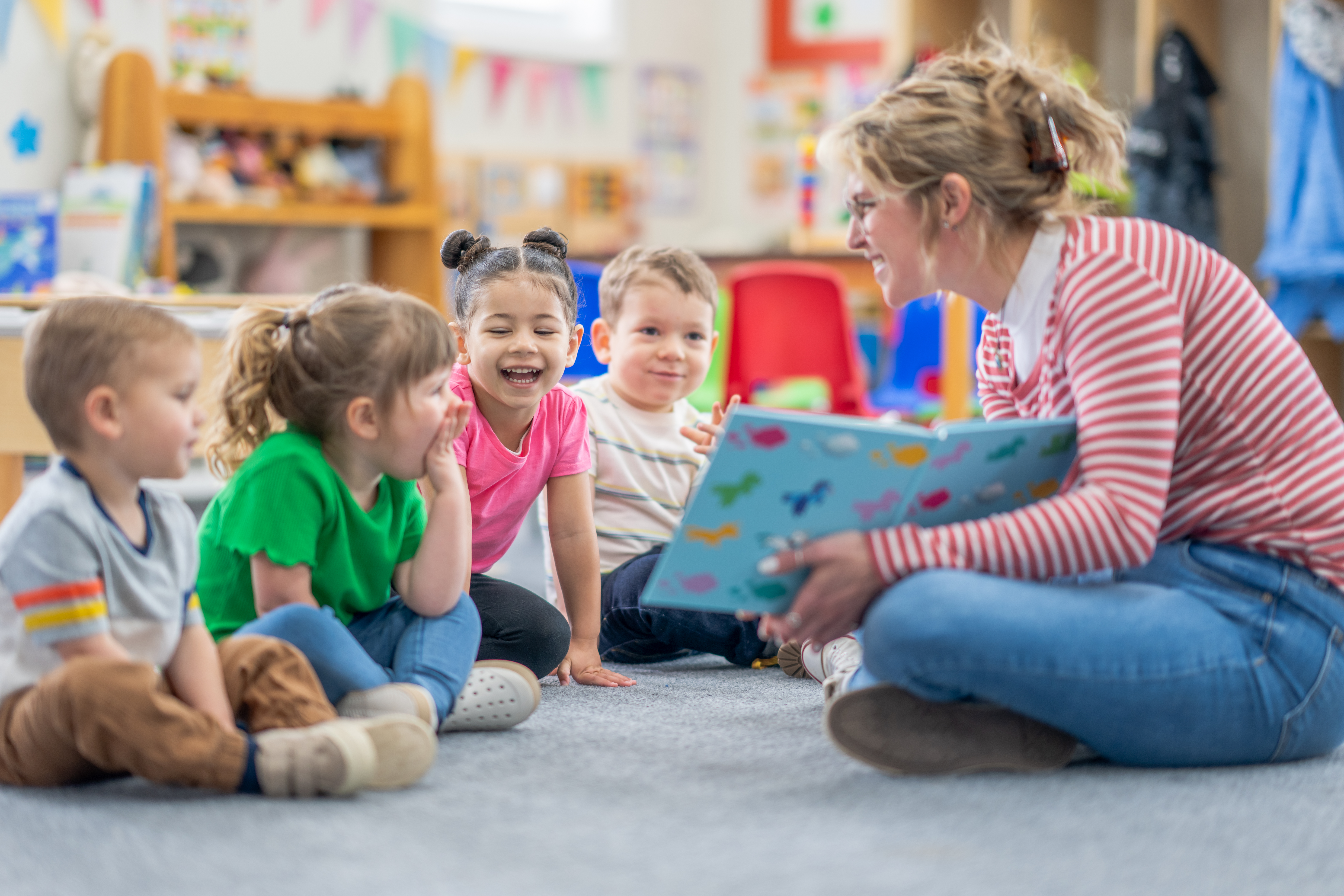 teacher with young students reading a book to them
