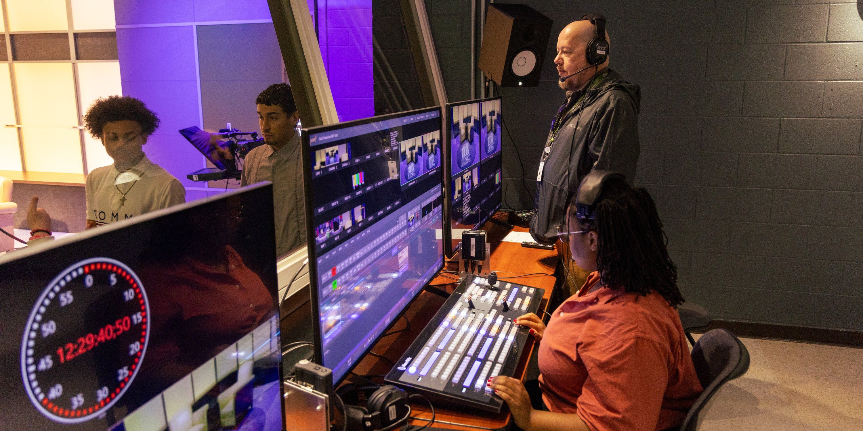 Mass Communications TV studio control room, a student working the controll board under the direction of visiting professional director from PBS to record an interview with Davide Crabtree.