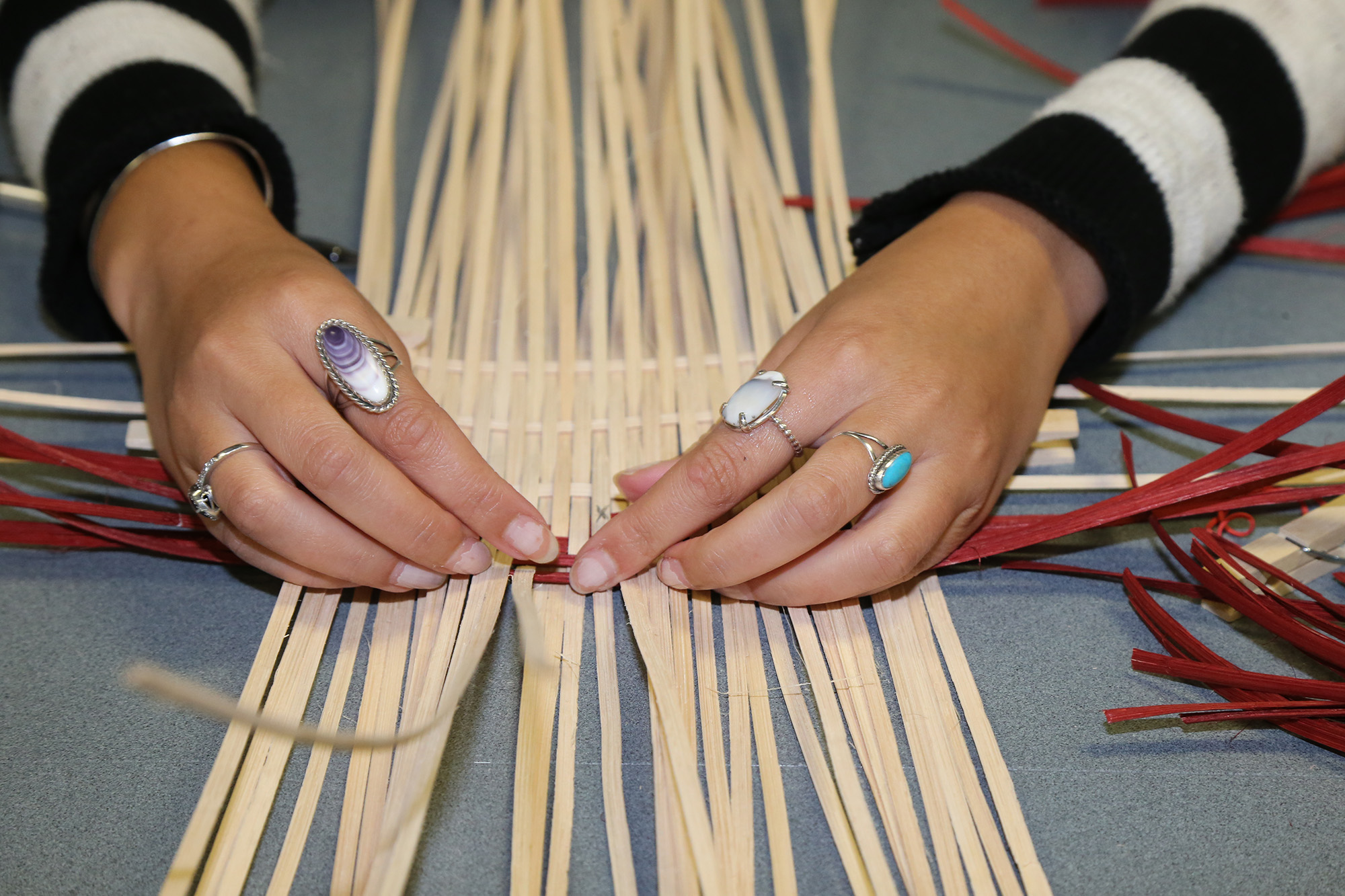 A pair of hands weaves a basket