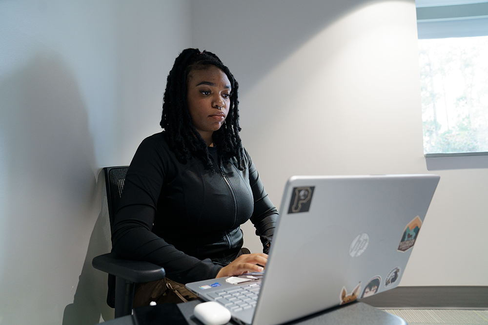 Female Reach Fellow works on a computer at UNC Pembroke
