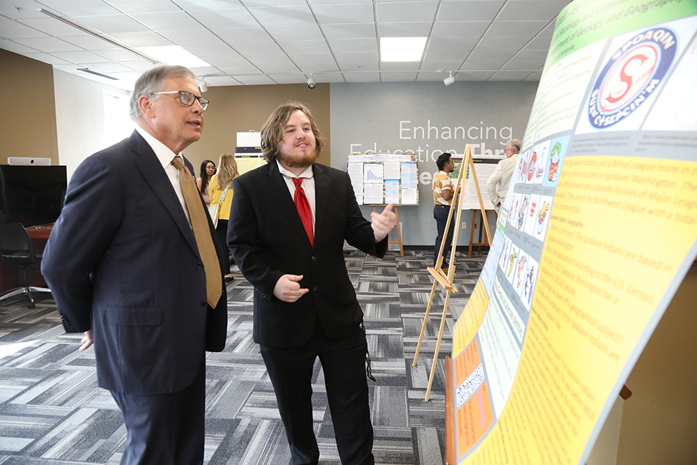UNC Pembroke Chancellor and a Reach Fellow discuss research at a symposium