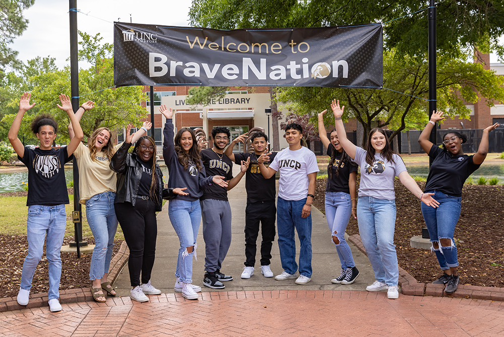 students at UNCP in front of banner cheering