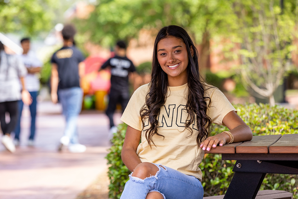 young UNCP student at a picnic table on campus