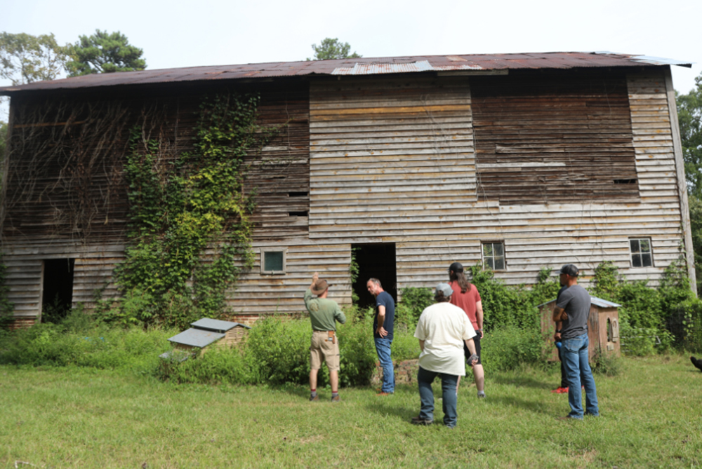 Agriculture students and faculty visit a historic barn during an educational small farm field trip.