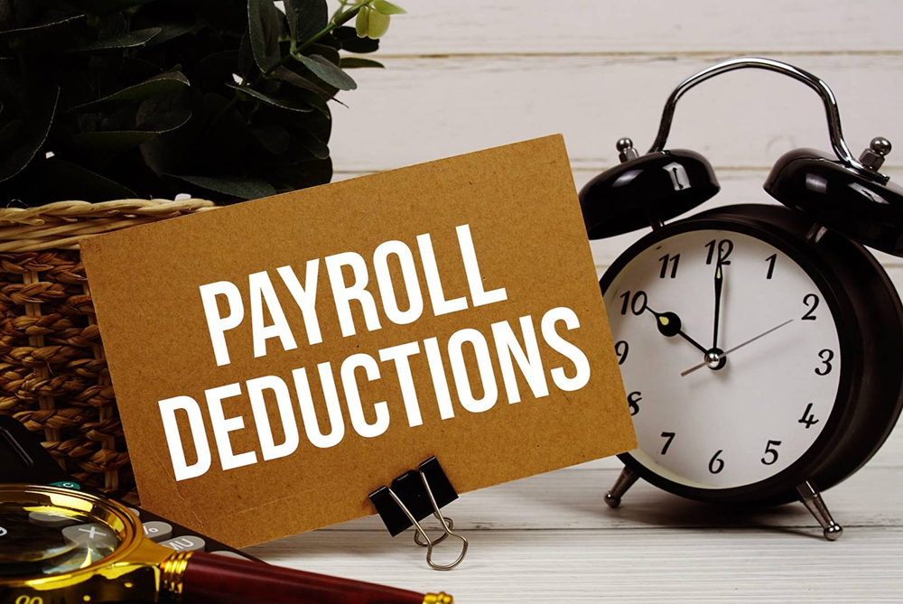 Photo with a clock and paper that says payroll deductions