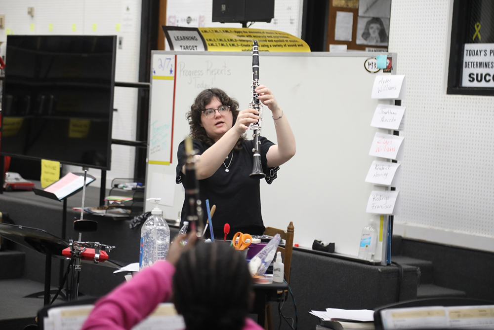 Female UNC Pembroke student teacher in a music class demonstrating finger position on an oboe.