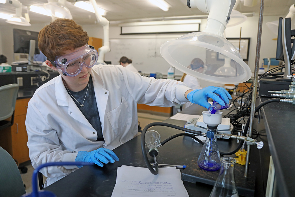 Mark McClure lab Chemistry student pouring liquid with goggles on