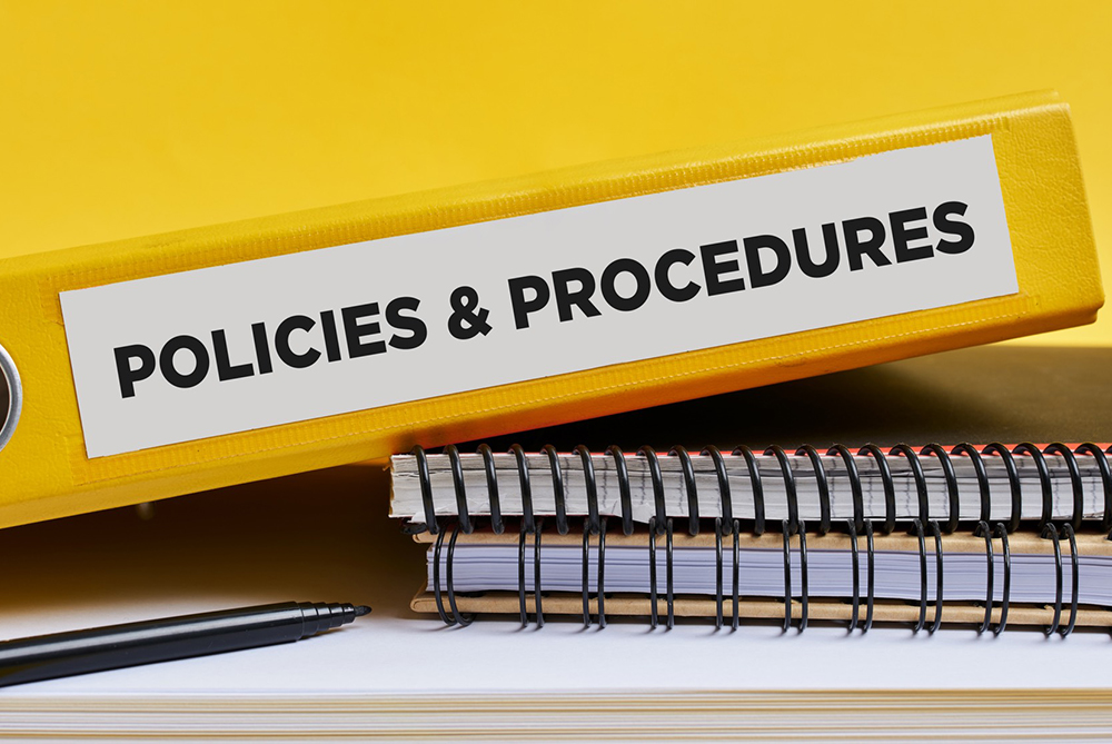 Policies & procedures binder on a desk