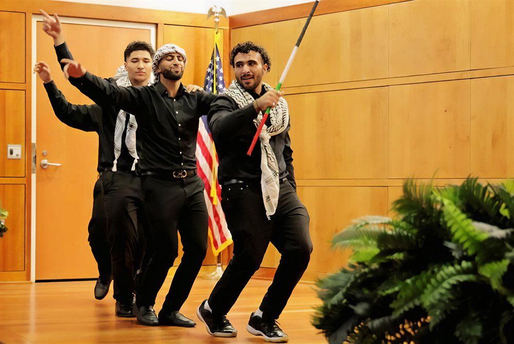 Four Middle-Eastern men dancing at a cultural show at UNC Pembroke.