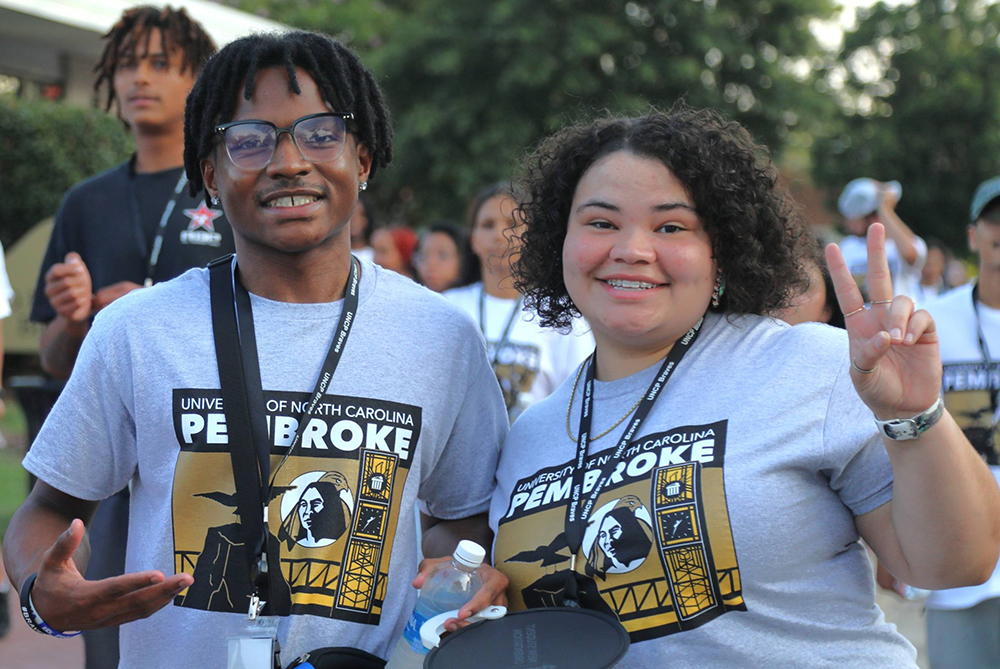 Male and femal freshman smiling and posing for the camera in UNC Pembroke t-shirts during the freshman brave walk across campus.
